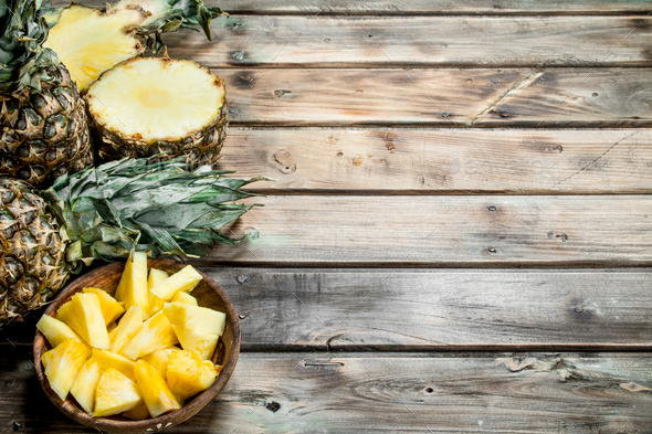 Sliced pineapple in a bowl on a cutting Board with a knife and a whole  pineapple. Stock Photo by Artem_ka2