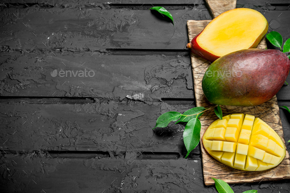 Whole and pieces of mango on the cutting Board.