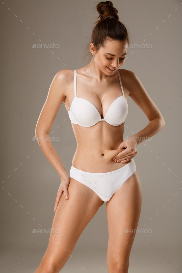 Woman pinching skin on her belly checking subcutaneous body fat
