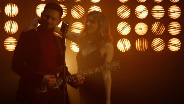 Attractive Guy Playing Guitar with Girl Dancing in Club alt