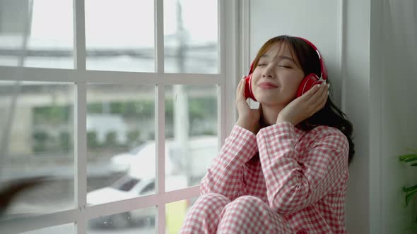Asian girl sitting lonely listening to music in the window, lifestyle concept, social distancing