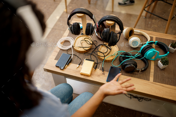 Woman choosing headphones in speaker systems store