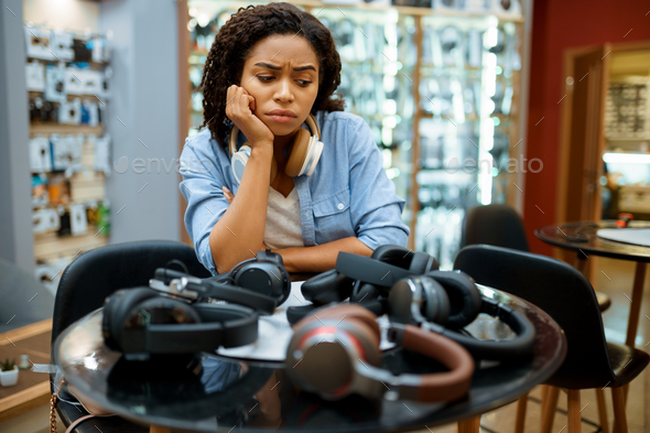 Woman choosing headphones in speaker system store