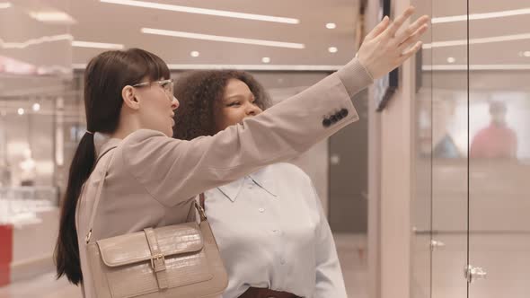Two Girlfriends Looking at Shop Window and Chatting alt