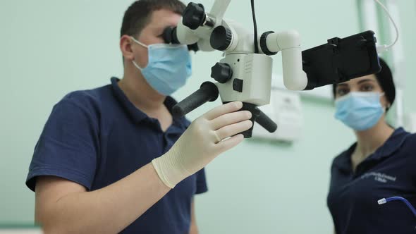Dentist Using Dental Microscope and Examining Woman's Teeth