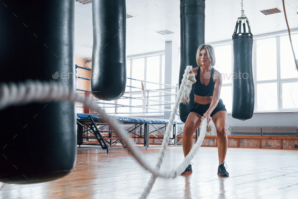 Pushing bags hanging around. Blonde sport woman have exercise with ropes in  the gym. Strong female Stock Photo by mstandret