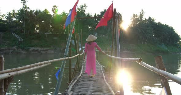 Vietnamese Girl In Traditional Dress Walking On Bamboo Bridge Cross River alt