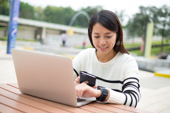 Woman connecting smart watch and cellphone at outdoor cafe