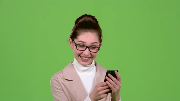 Business Lady Looks at Photos on Her Smartphone. Green Screen. Slow Motion alt