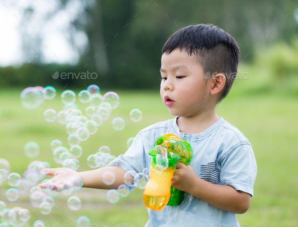 Young boy play with bubble gun and touch on the bubble