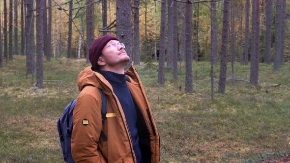 Caucasian Man Wearing Backpack Standing Over Forest Background