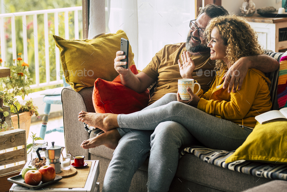 Adult happy couple man and woman at home enjoy morning breakfast and do video phone call - Stock Photo - Images