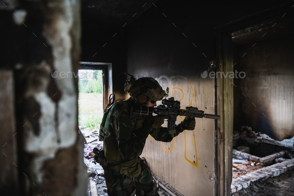 Soldier in full US MARSOC armed with assault rifle run through the abandoned building. Military