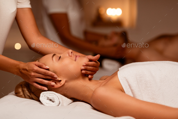 Spouses Receiving Relaxing Beauty Treatment Lying At Luxury Spa