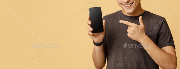 Modern digital ad on device. Cheerful teen male points finger at smartphone