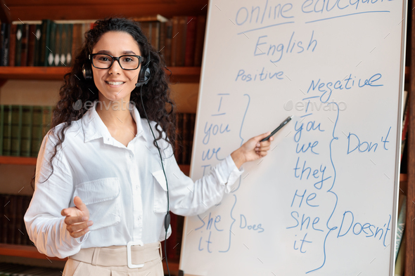 Smiling female teacher standing near whiteboard, explaining rules