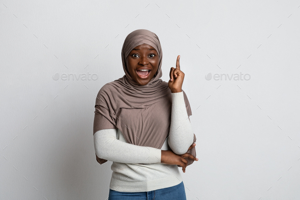 Excited Black Islamic Lady In Headscarf Having Idea, Pointing Finger Up