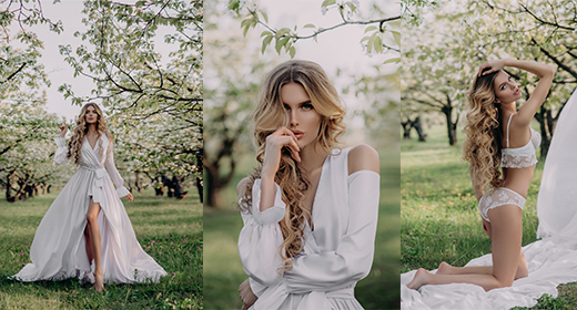 Young woman with blonde hair wrapped in white cloth walking alone between trees in apple garden