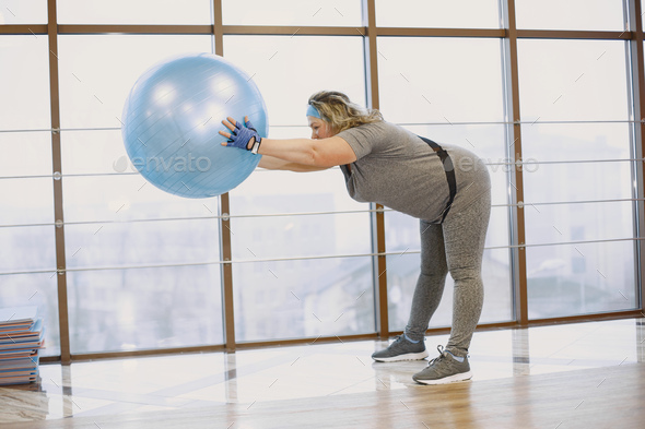Adult fat woman doing gymnastics at the gym