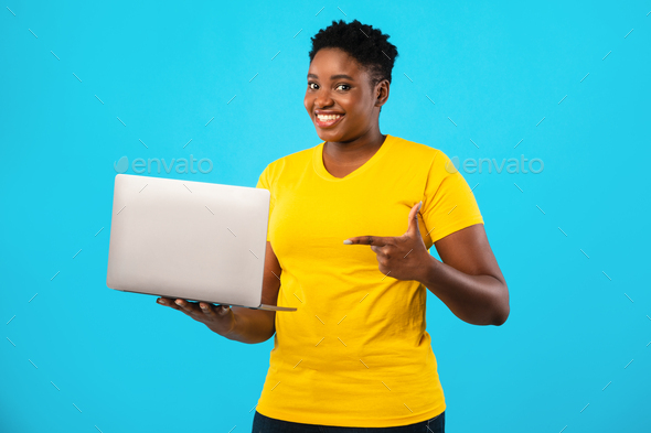 Oversized Black Woman Pointing Finger At Laptop Over Blue Background