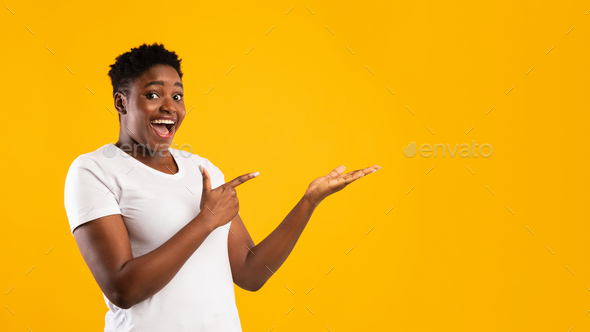 Excited Plus-Size Black Woman Pointing Fingers Aside, Yellow Background, Panorama