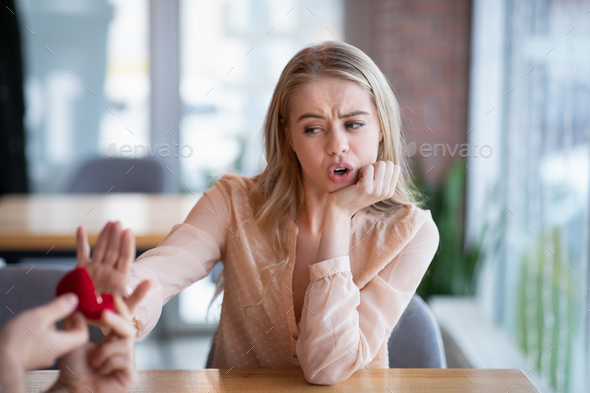 Irritated millennial woman not accepting engagement ring from her boyfriend, rejecting marriage