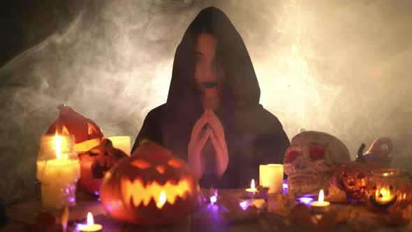 Girl in Mantle with Hands Together Raises Her Head and Takes the Hood Off alt