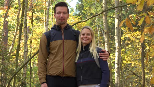 A Hiking Couple Talks To the Camera in a Forest on a Sunny Day alt