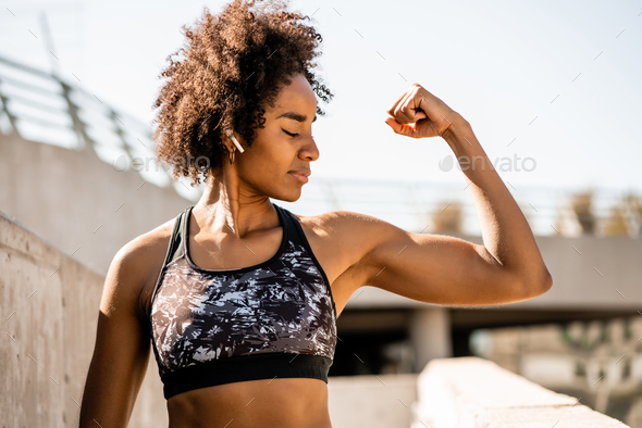 Afro athlete woman flexing and showing muscles. Stock Photo by megostudio