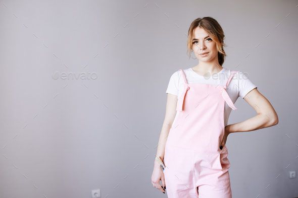 A woman in a pink in work clothes is looking at the camera