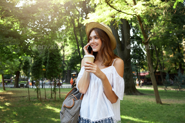 portrait of happy beautiful young woman wears stylish hat, white blouse and striped backpack