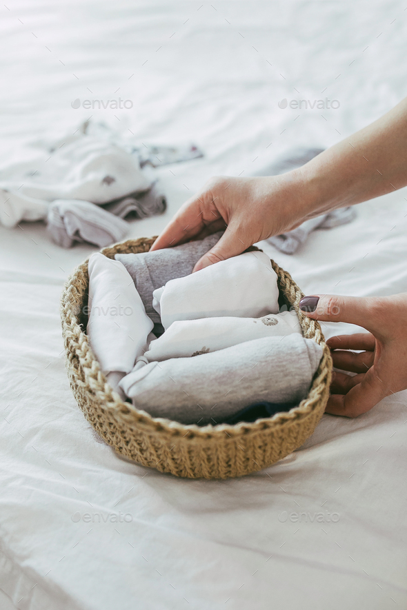 Woman folding clothes in jute basket in the konmari system. Concept of organizing minimalism clothes
