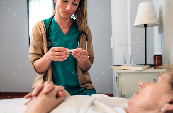 Doctor taking temperature to senior woman