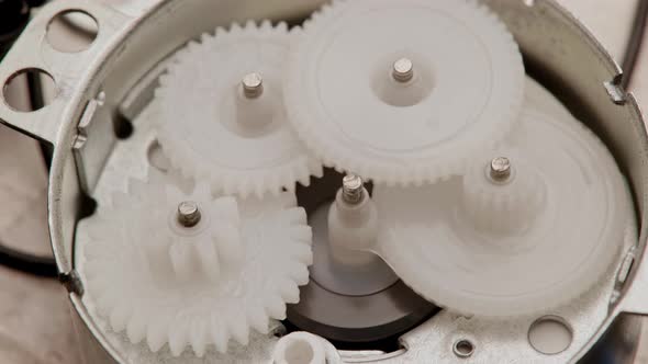 Five Plastic Gears Rotate in Mutual Mesh Inside a Small Reduction Gear alt