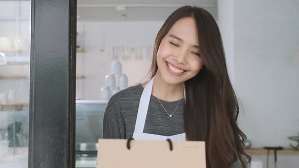 Asian waitress delivering takeaway coffee and food bags to customers alt