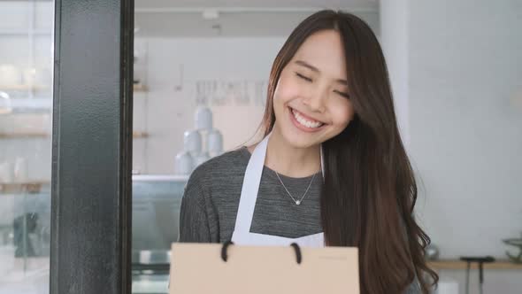 Asian waitress delivering takeaway coffee and food bags to customers