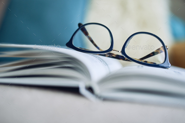 Soft focus glasses, book on the sofa. Abstract book blur background.