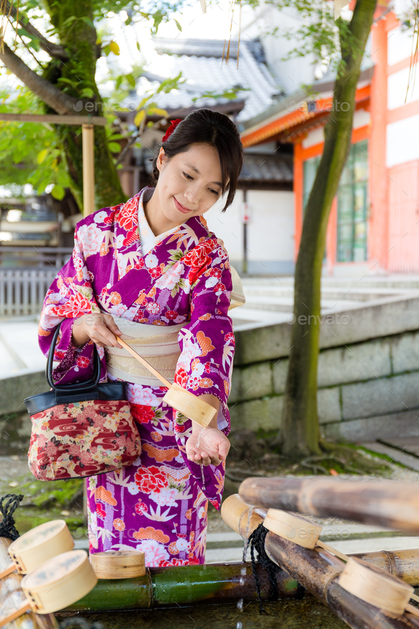 Young japanese woman use of the bamboo ladle in water fountain