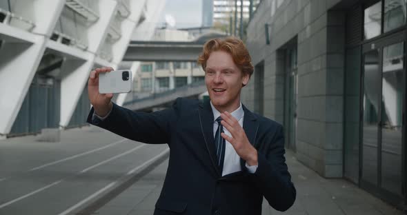 Smiling Handsome Redheaded Business Man Having Selfie Video Chat Using Smartphone Outside at City alt