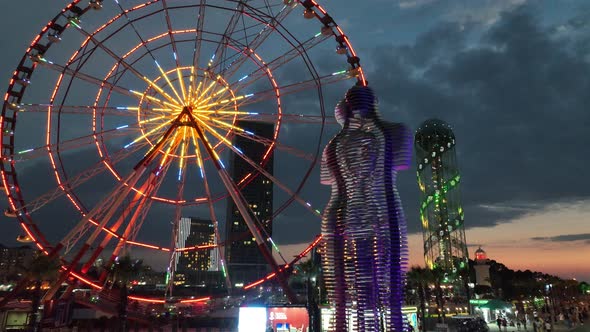 Flying over the moving statues of man and woman, Ali and Nino at sunset alt