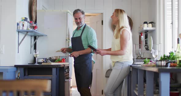 Happy caucasian mature couple cooking together and using tablet alt