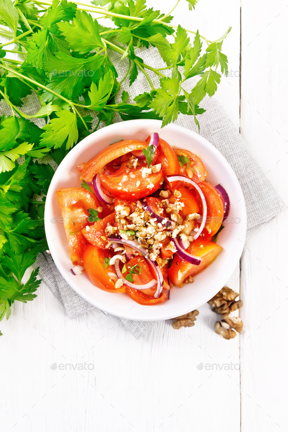 Salad with tomato and walnut in plate on light board top - Stock Photo - Images