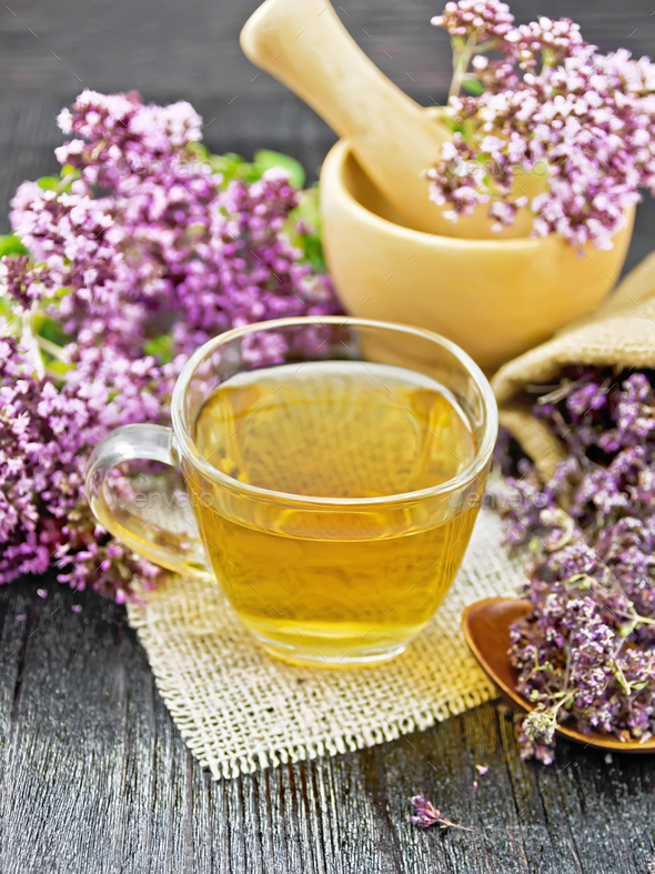 Tea of oregano in cup with mortar on dark wooden board - Stock Photo - Images