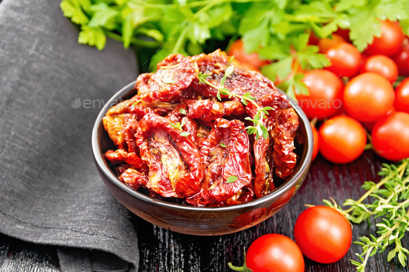 Tomatoes sun-dried in bowl with napkin on black board - Stock Photo - Images