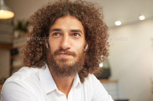 Close-up portrait of attractive young male with beard, having long curly  hair and brown kind eyes Stock Photo by nakaridore