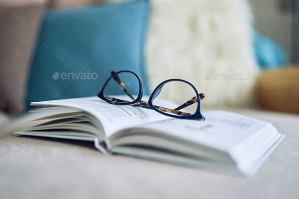Soft focus glasses, book on the sofa. Abstract book blur background.