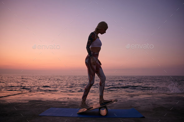 Young healthy blonde female with good body shape wearing sporty clothes, doing exercise