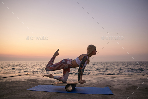 Outdoor shot of young sporty blonde woman in good physical condition doing exercises