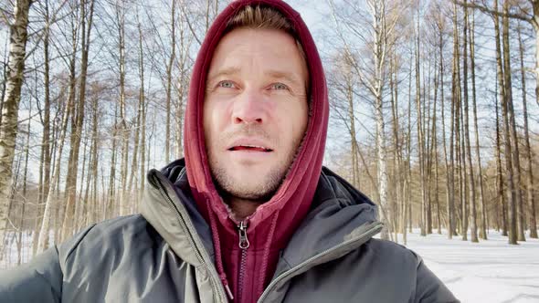 a Young Men is Walking in the Park is Wearing a Sweatshirt with a Hood and a Down Jacket the Young alt