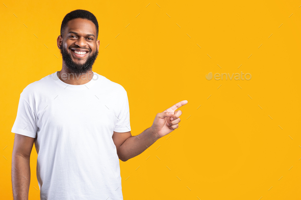 Black Man Pointing Finger Aside Standing Over Yellow Studio Background